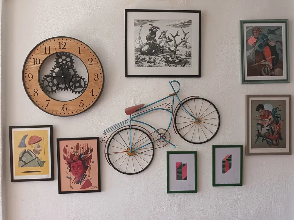 Pared interior del Hostal Louro decorada con una bicicleta metálica, un reloj de pared y varias ilustraciones enmarcadas.