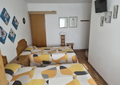Habitación doble con dos camas separadas en el Hostal Louro en Ordes, con mobiliario funcional y ambiente tranquilo.