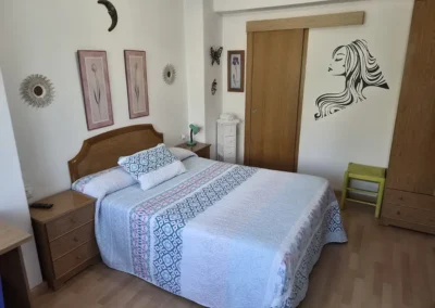 Habitación doble con cama de matrimonio en el Hostal Louro en Ordes, con mesillas, armario.