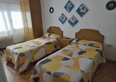 Habitación tipo twin del Hostal Louro en Ordes, con dos camas separadas, armario y mobiliario funcional.