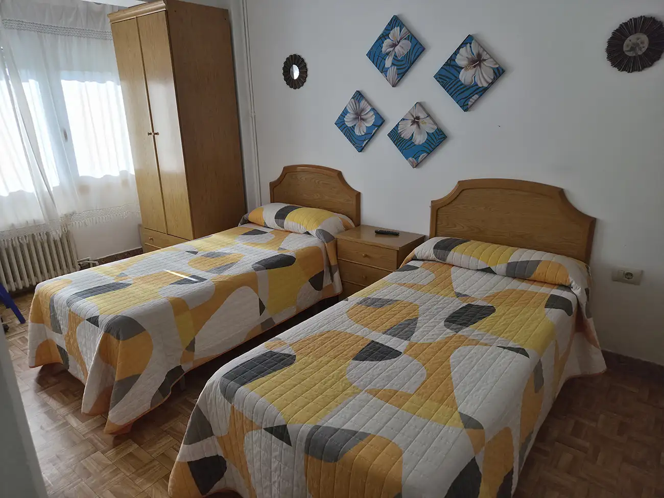 Habitación tipo twin del Hostal Louro en Ordes, con dos camas separadas, armario y mobiliario funcional.