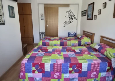 Habitación con dos camas individuales en el Hostal Louro en Ordes, equipada con armario, mesilla y luz natural.