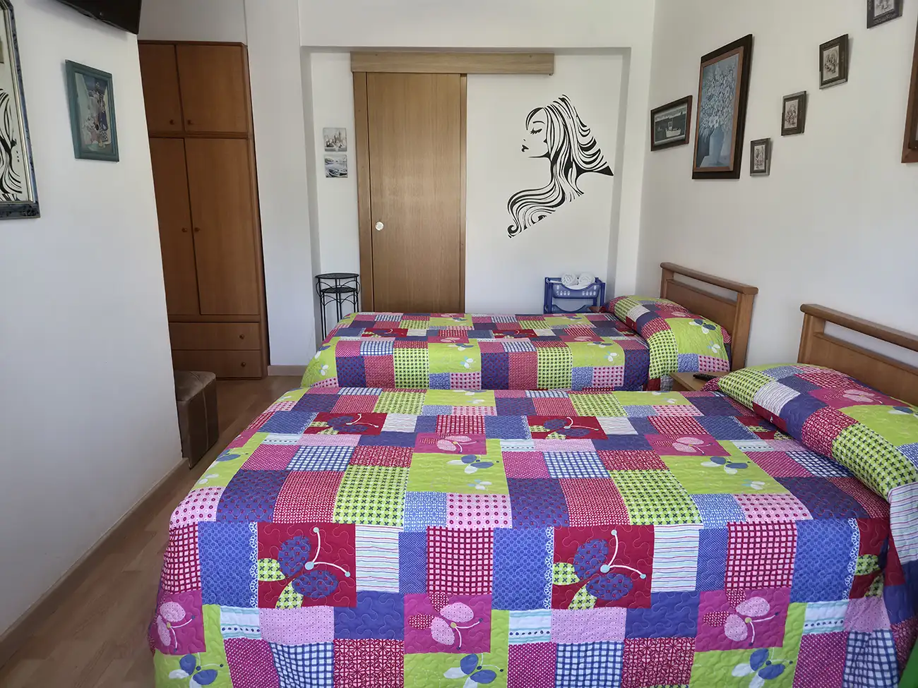 Habitación con dos camas individuales en el Hostal Louro en Ordes, equipada con armario, mesilla y luz natural.