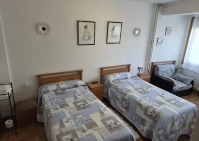 Habitación con dos camas individuales en el Hostal Louro en Ordes, con mobiliario sencillo y luz natural.